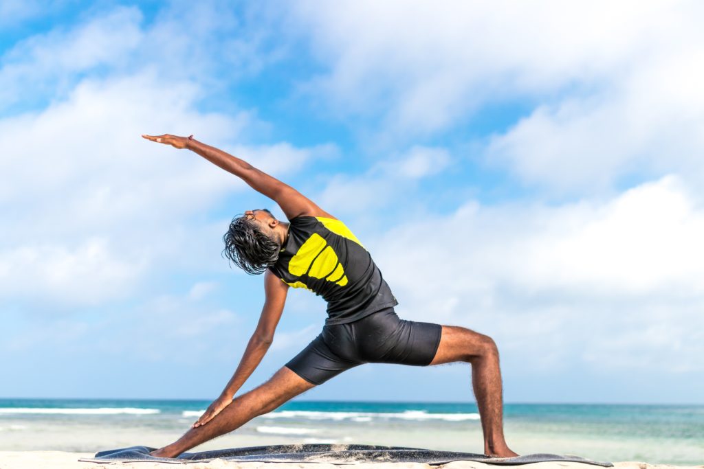 Man doing yoga at the beach