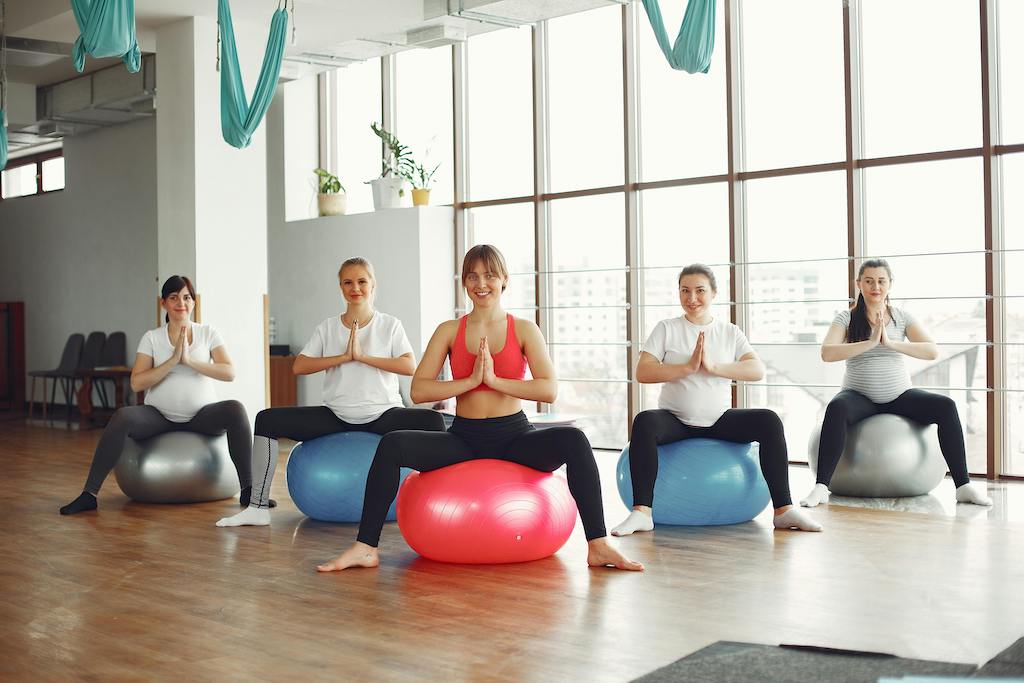 Group of pregnant women participating in a supportive pre-natal exercise class