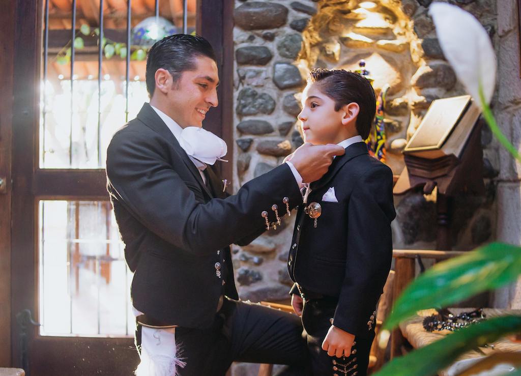 Man dressing his son in traditional Mexican mariachi dress