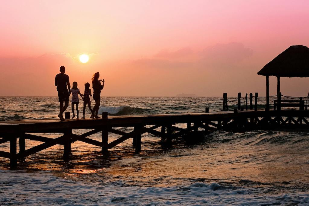 Family walking together on a jetty at sunset. 